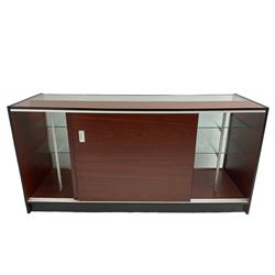 Shop display cabinet counter, glazed front and top, with mahogany laminate sides and back, enclosing two long adjustable shelves, fitted with two sliding cupboard doors to the rear, on castors