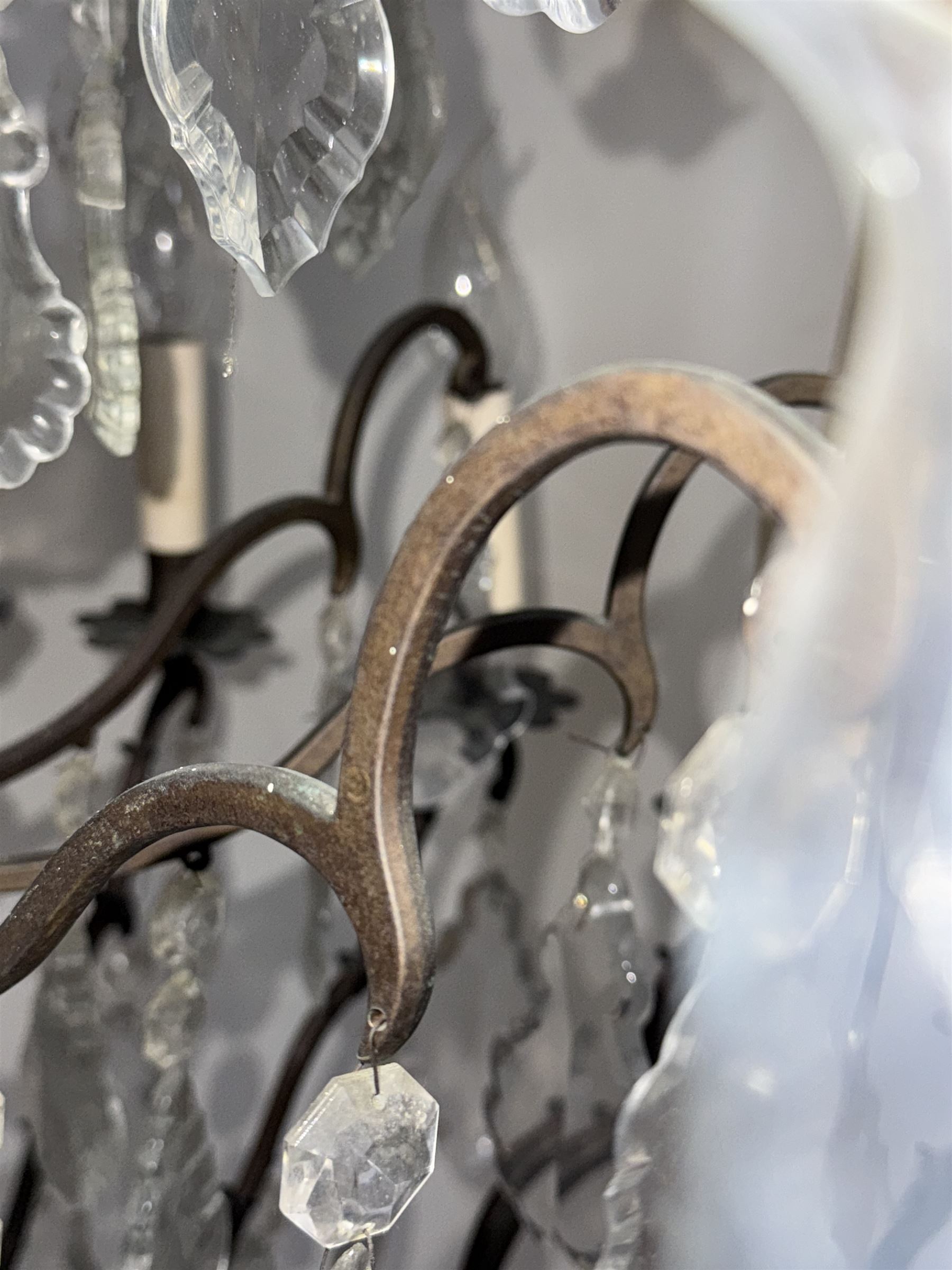 Early 20th century continental cut glass and metal chandelier, with sixteen candle style lights on a single tier of scrolled arms, hung with faceted glass drops and centred by a mould-blown and cut glass baluster stem, suspended from a ceiling rose and chain