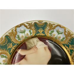 Two late 19th century cabinet plates in the manner of Vienna, both finely painted with a portrait of a female beauty, the first depicting semi nude classical lady within an ornate gilt border painted with white flowers and foliage on alternating teal and light blue ground, the second depicting a lady in pink dress adorned with flowers within white border with raised gilt foliate motifs, interspersed with four deep red roundels with gilt garden scenes, both marked Wagner and with blue beehive marks, one marked Dresden, and entitled 'Babarere' and Ustana, D25cm