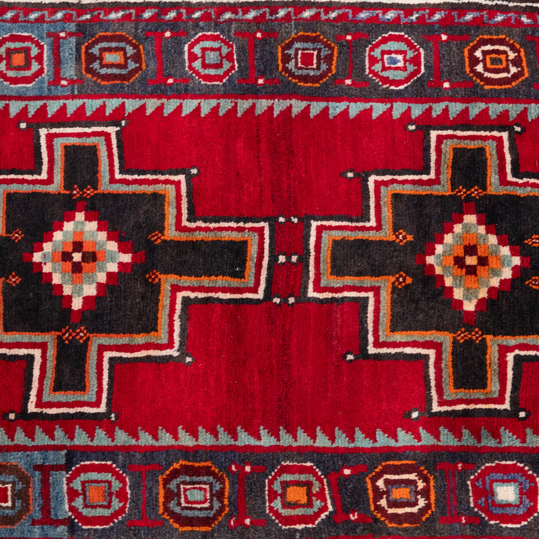 South-west Persian Lori rug, the red field centred by four linked stepped cruciform medallions with polychrome diamond centres, enclosed by a blue ground octagonal motif border, ivory angular meander band and red geometric outer border