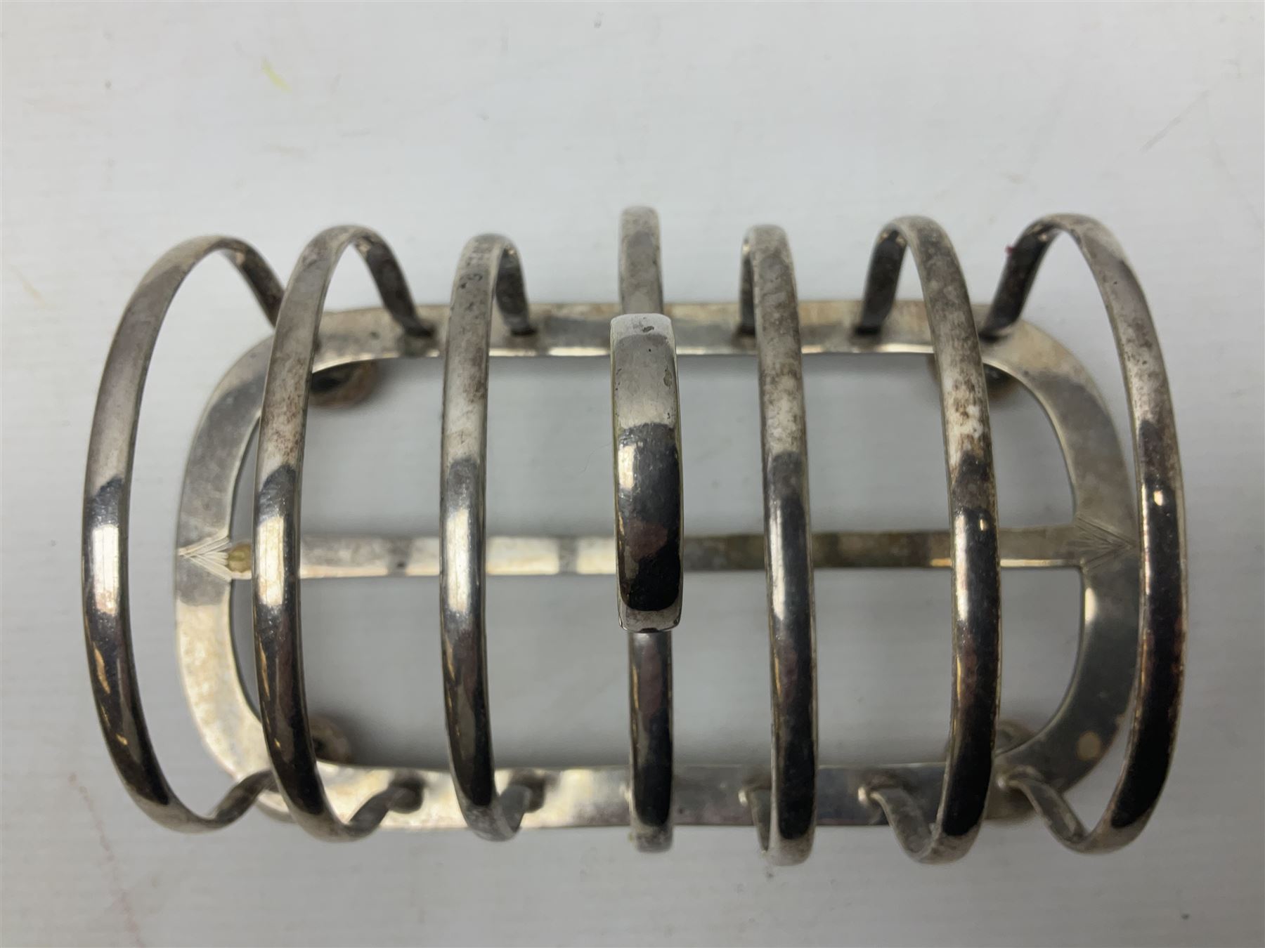 Silver plate seven bar toast rack, of curved form with central ring handle, upon bun feet, H13cm 
