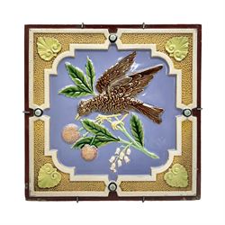 19th century Minton & Co majolica tile, decorated in relief with a bird upon a fruiting branch against a blue ground, with textured ochre border and anthemion to each corner, impressed mark verso, H19.7cm