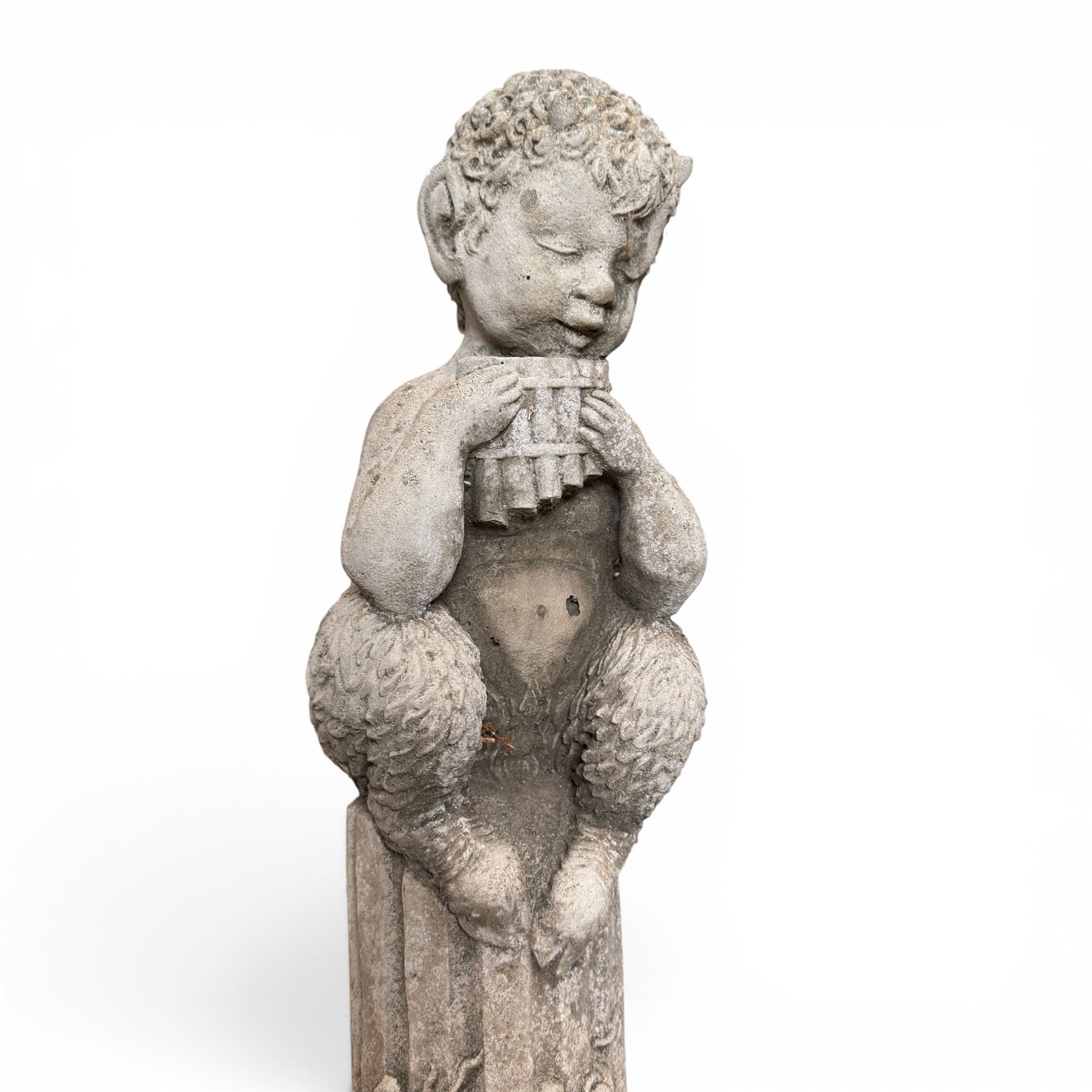 Pair of weathered composite stone garden figures, modelled as a girl and a young satyr playing the panpipes seated on column supports, the fluted columns with climbing ivy vines and surmounted animal, butterfly and other zoomorphic motifs