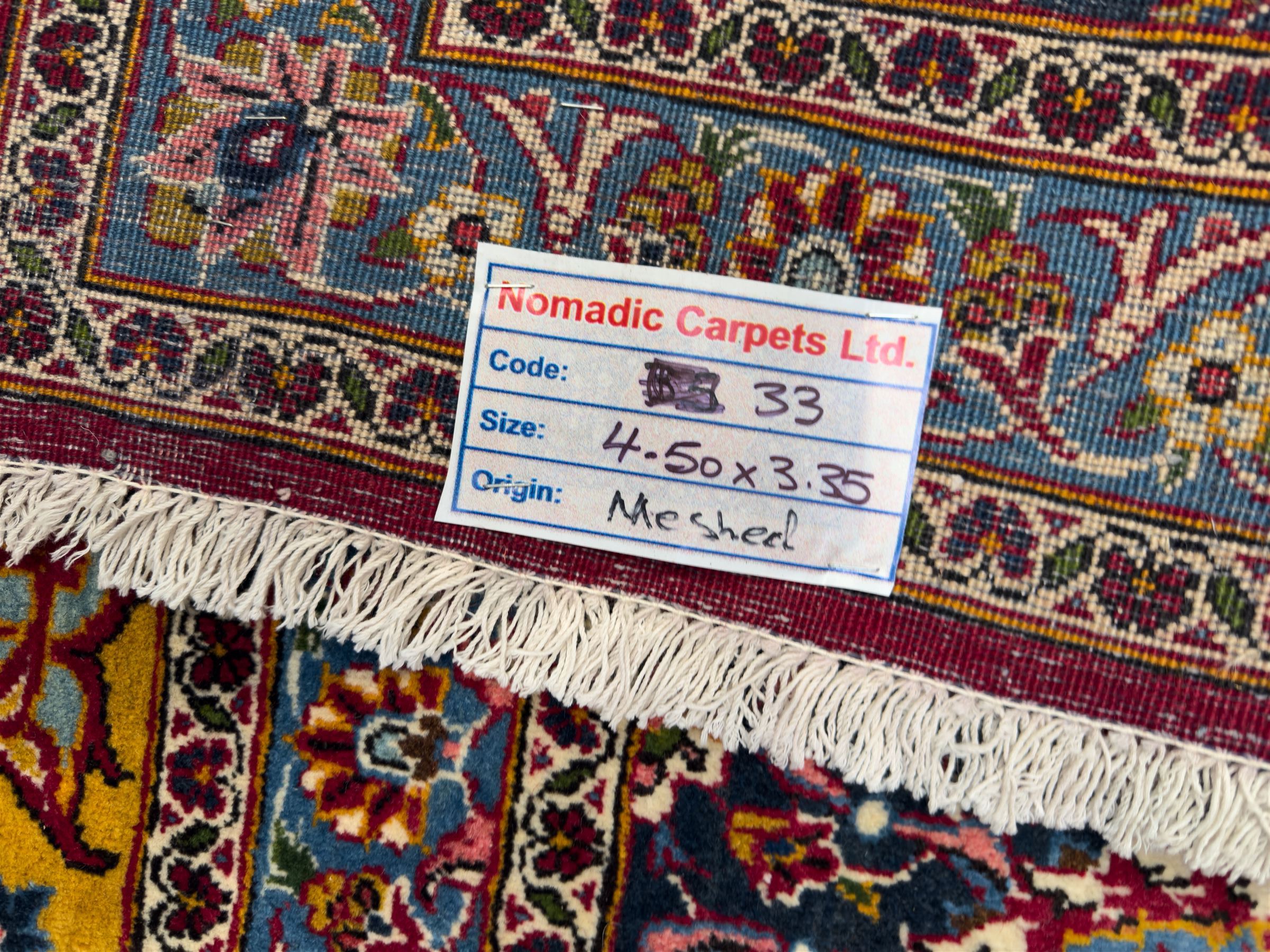 Central Persian Kashan hand-knotted carpet, madder red field with an intricate design of scrolling vines, palmettes, and rosettes with a central lobbed medallion with pendant motifs in shades of blue and ivory, and spandrels all within a blue-ground border of palmettes and flowerheads between multiple guard borders, 450cm x 335cm 
