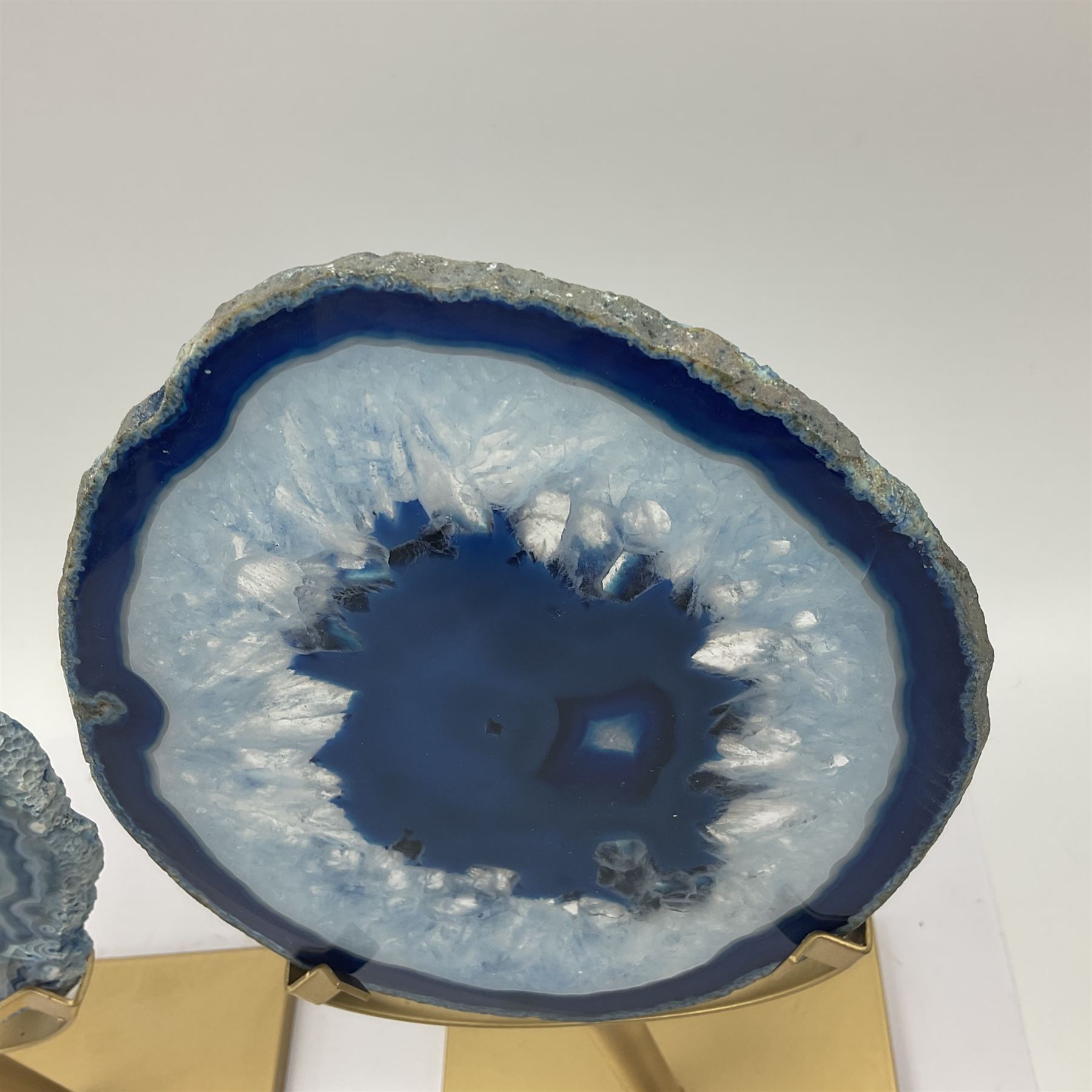 Pair of blue agate slices, polished with rough edges raised upon gilt metal stands, H22cm