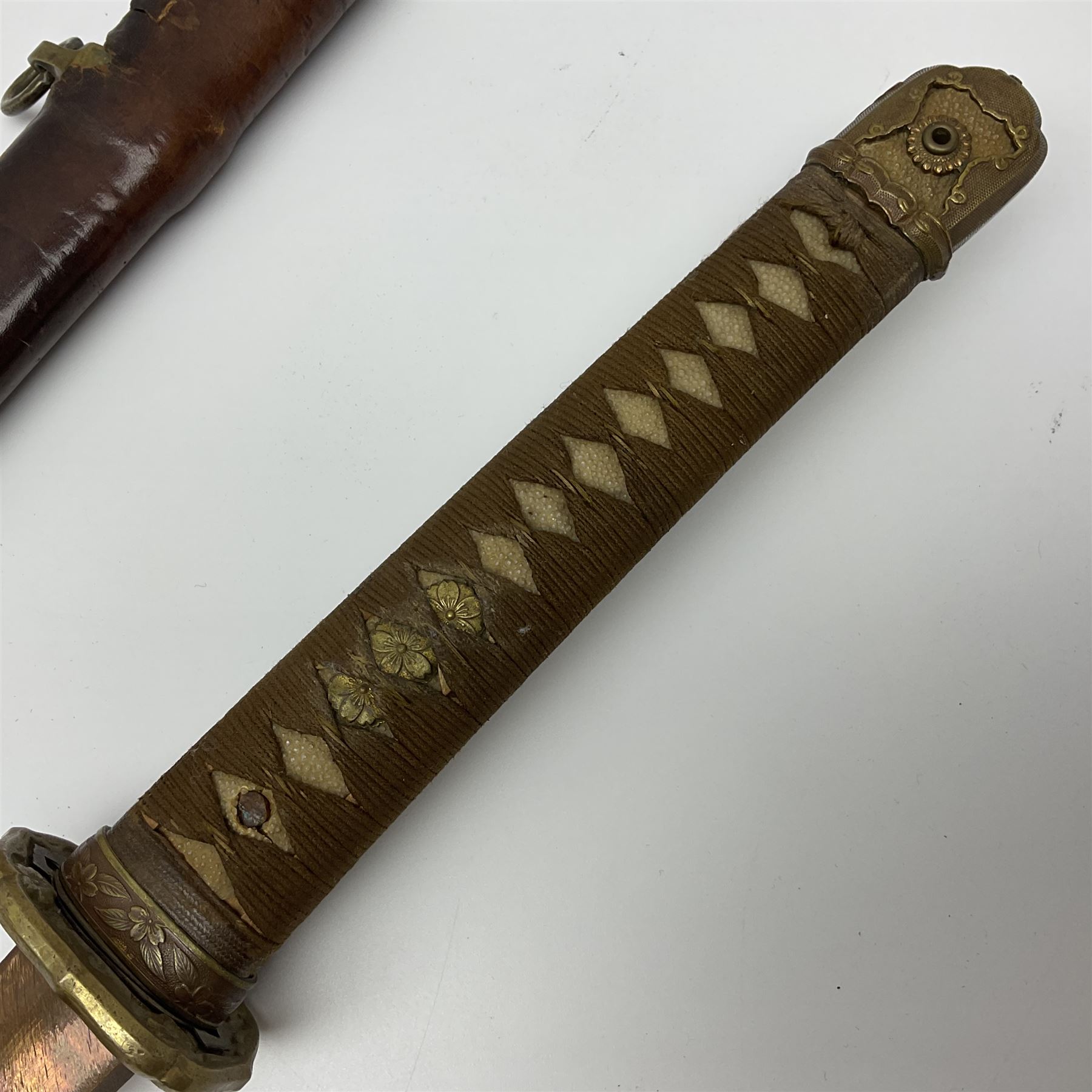 WW2 Japanese Army officer's shin gunto/katana sword with 67cm steel single edged blade, foliate cast brass tsuba, bound fish-skin grip with brass mounts, inscribed and painted marks to tang; in lacquered wooden scabbard with leather combat covering bearing four character marks L99cm overall