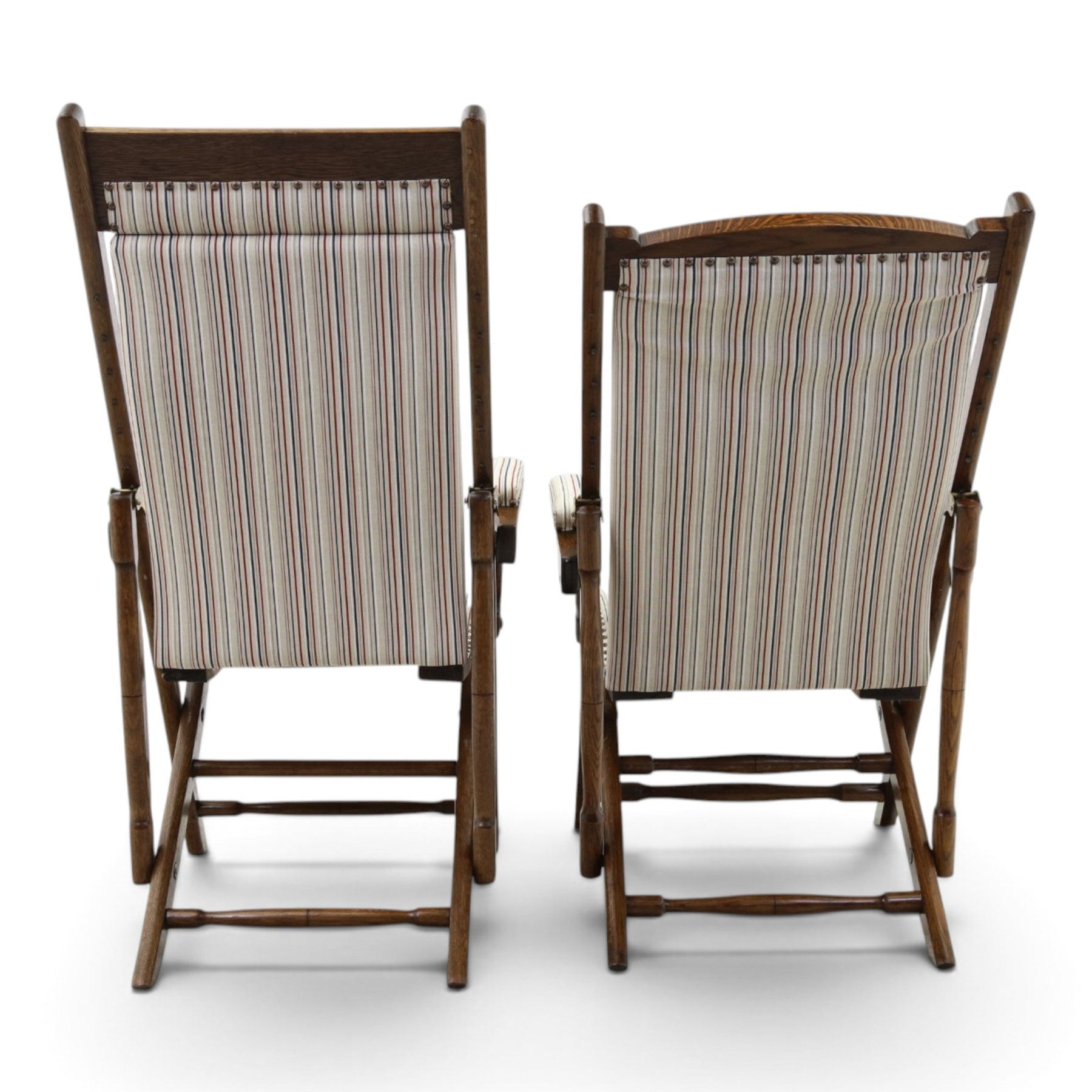 Pair of early 20th century oak framed garden reclining and folding deckchairs, high back and seat upholstered in striped fabric with padded armrests