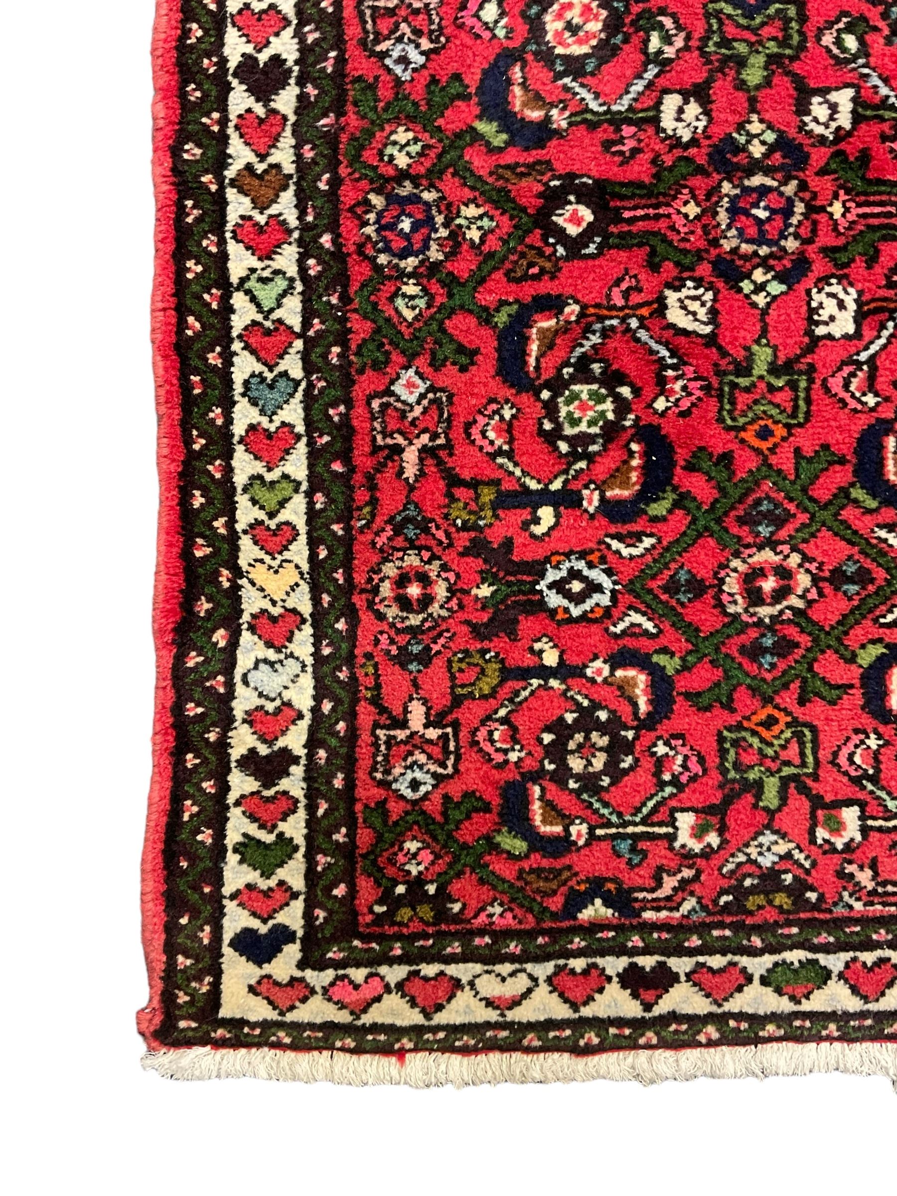 Persian red ground runner, decorated with large Herati motifs and shaped central medallion, the guarded border decorated with repeating heart motifs