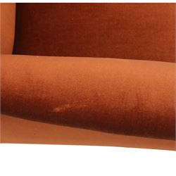 Late 19th century mahogany framed armchair, of generous proportion, upholstered in rust coloured velvet, with shaped back and scroll arms, raised on turned front legs with brass castors