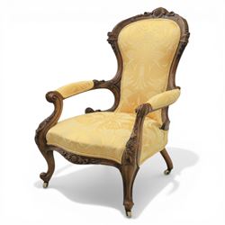 Victorian carved walnut open armchair, shaped and moulded frame with foliate carved cresting rail, upholstered back and seat in yellow damask fabric, scroll arms with padded rests, carved cabriole supports terminating in ceramic castors
