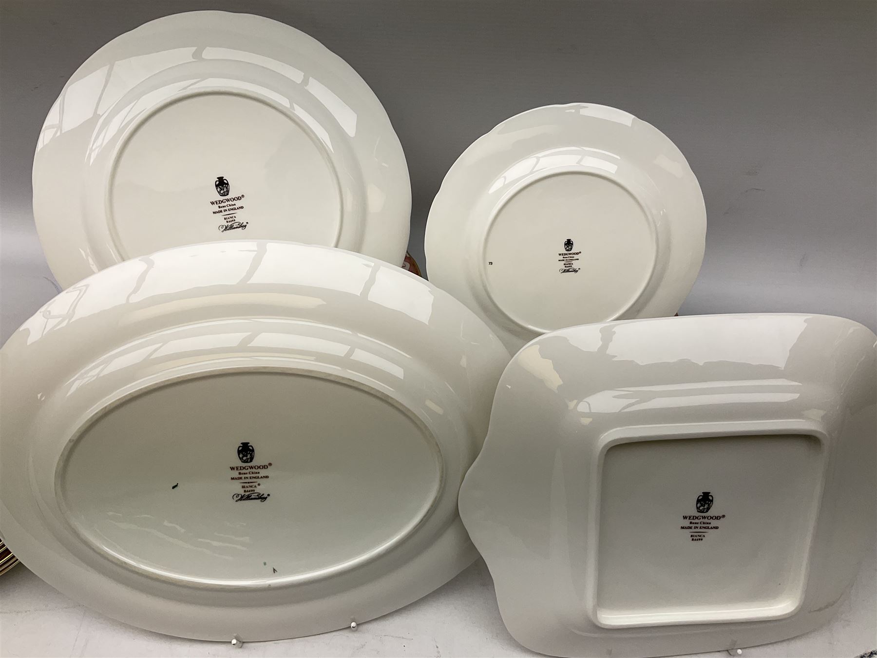 Wedgwood dinner service decorated in the 'Bianca' pattern, to include eight dinner plates, eight bowls, eight side plates, eight twin handled souo bowls, eight soup bowl saucers, eight teacups, eight teacup saucers, six dessert plates and two larger, two twin handled lidded tureens, milk jug, two sauce boats, salt and pepper shakers, oval serving  plate, twin handled sandwich plate, covered sucrier, small rectangular dish and two small circular dishes, all with printed stamp mark beneath