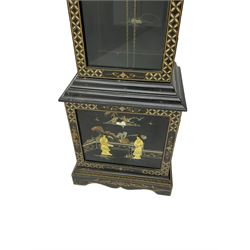 20th century 8-day chain driven black lacquered longcase clock - with a swans neck pediment and break-arch hood door, fully glazed trunk door displaying brass cased weights and pendulum, case sides, hood and plinth profusely decorated in gold relief and chinoiserie figures, brass break arch dial with an etched centre and silvered chapter ring, German two train movement striking the hours and half hours on two gong rods. With weights and pendulum.
