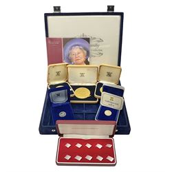 Two Isle of Man one pound coins in cases with certificates, three Queen Elizabeth II 1952-1977 Silver Jubilee commemorative medallions, an empty coin box and a Queen Mother commemorative five pound coin, in a blue coin display case