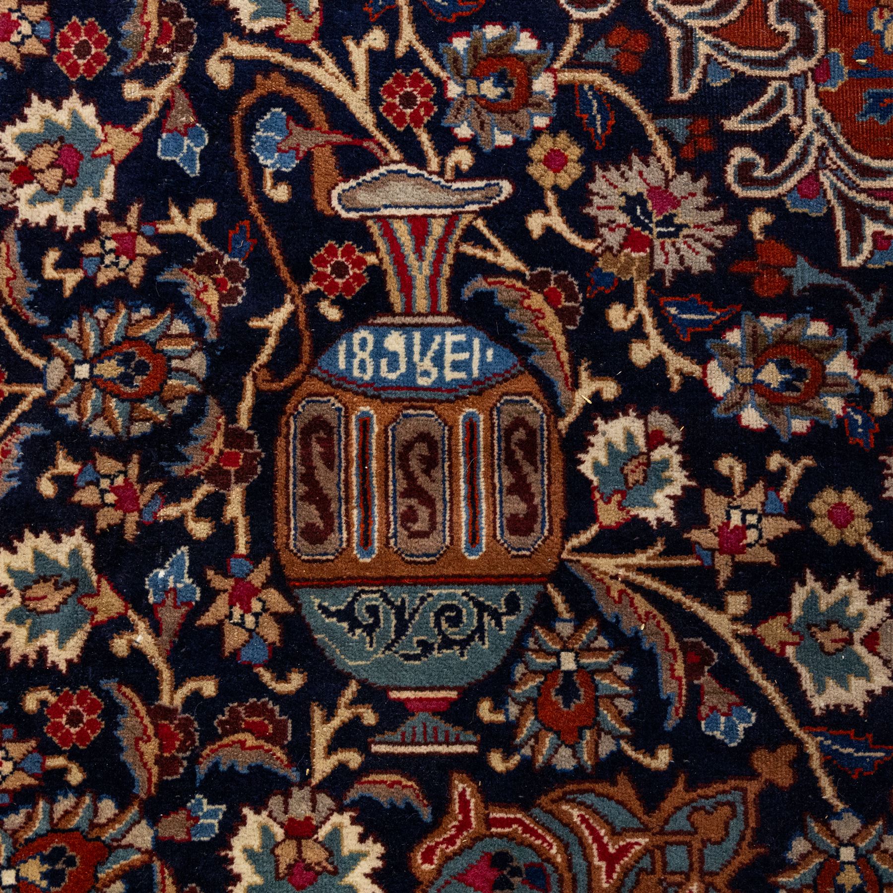 North East Persian Meshed hand-knotted carpet, deep navy field with central complex medallion and densely decorated scrolling floral sprays and palmettes, incorporating cartouche motifs enclosed by a broad tan and dark blue border ornamented by stylized vases flanked by multiple guard stripes, signed 'Amal-e Haji translates as the Work of Haji', with cotton fringe ends 