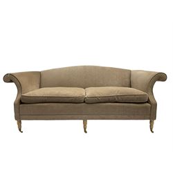 Traditional three seat sofa, curved back over scrolled arms, upholstered in crushed beige fabric with matching loose cushions, on turned front supports with brass and ceramic castors, together with matching footstool