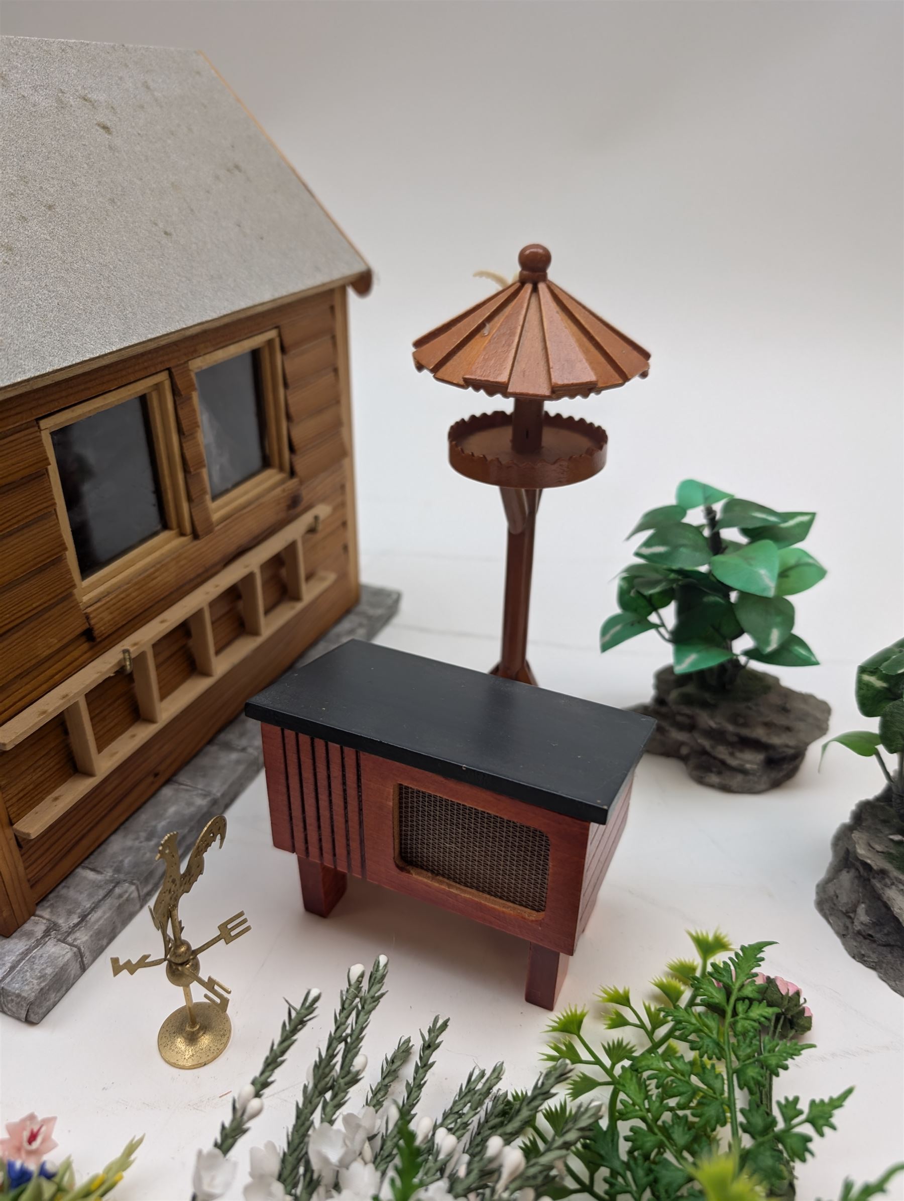 1:12 scale dolls house allotment and garden accessories, including wooden shed on a stone effect base, two vegetable patches, terracotta plant pots with flowers and foliage, stone effect plant pots, other planters, loose sunflowers, scarecrow, rabbit hutch, garden tools, fencing panels, etc 