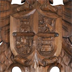 Carved wooden wall plaque, decorated with foliate scrolls, with two reproduction swords attached, together with five other wooden plaques with foliate scrolls and shields