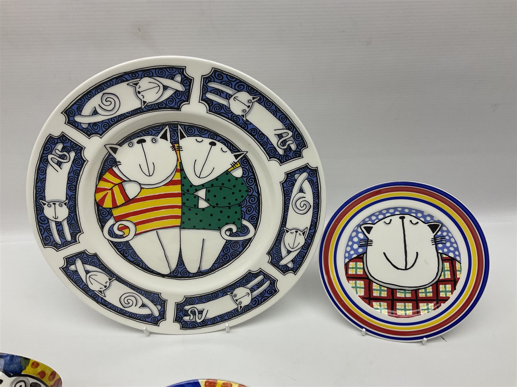 Modern studio pottery by Josie Firmin, to include cup and saucer, three espresso cups and saucers, pair of egg cups etc, each hand painted with varying cartoon cat designs