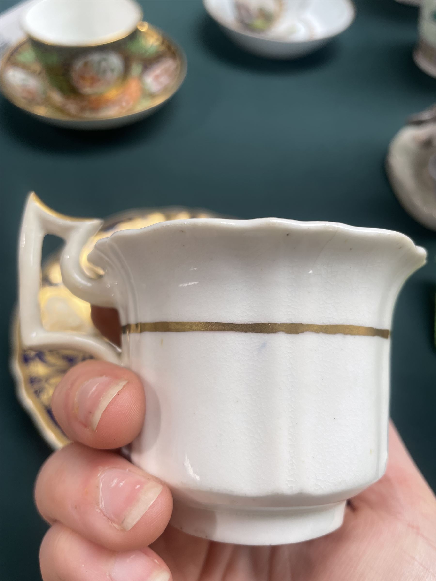 19th century teacup and saucer, possibly Coalport, decorated with panels of flowers on a cobalt blue ground with gilt decoration; together with two other teacup and saucer pairs, one with hand painted landscape decoration 