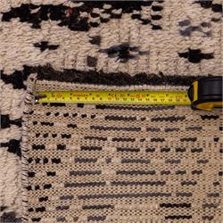 Moroccan hand-knotted Berber rug, of rectangular form, ivory ground woven with horizontal bands of stylized tribal motifs, including abstract animals and anthropomorphic figures, interspersed with geometric devices, with fringe ends 