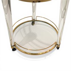 Hollywood Regency style gilt metal and glass serving trolley, circular top in a polished brass surround with three pineapple finials, supported on clear column legs, lower glass shelf enclosed by a brass gallery, terminating in castors