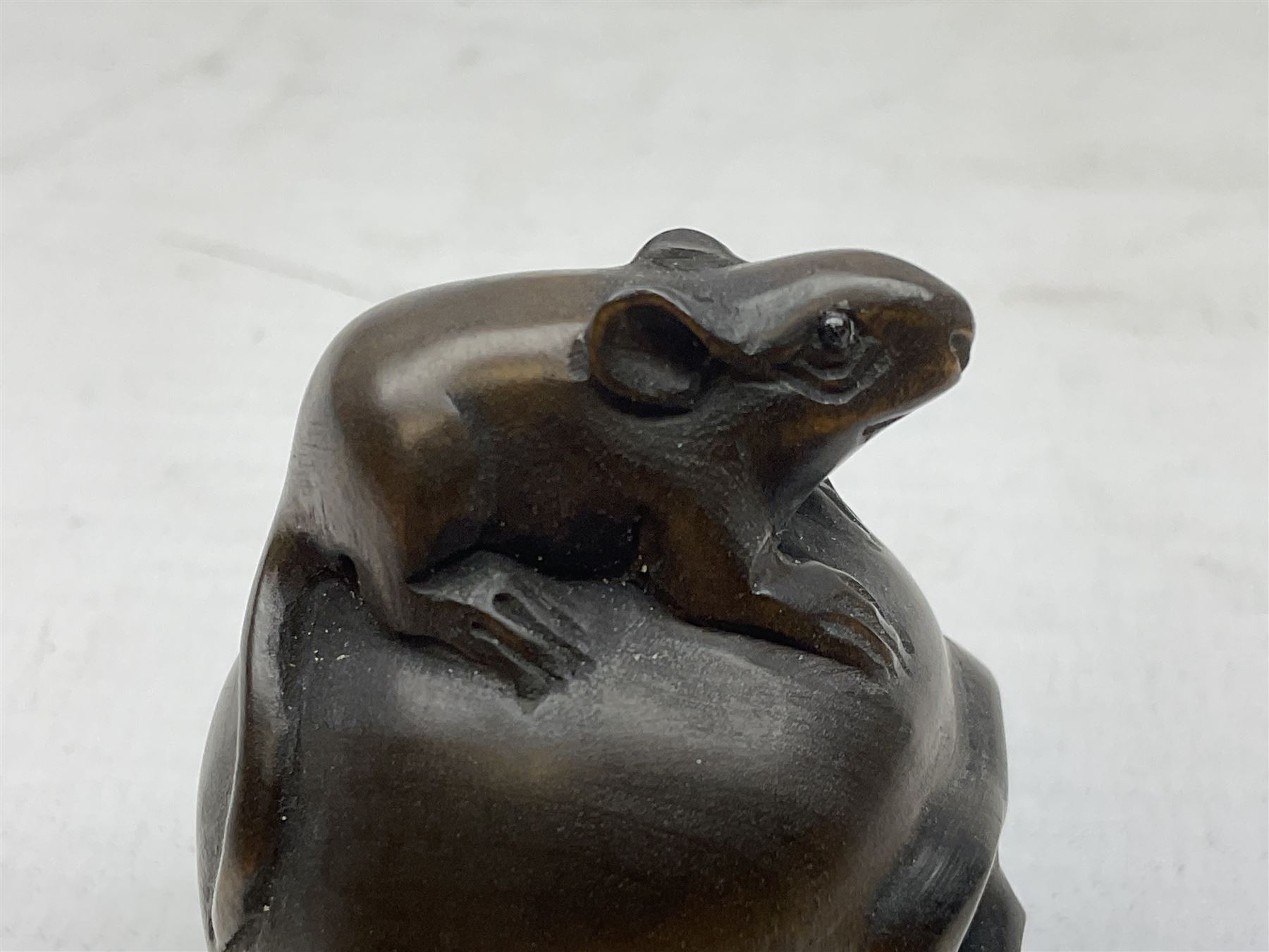 Netsuke in the form of a rat sitting on a skull, signed to the base