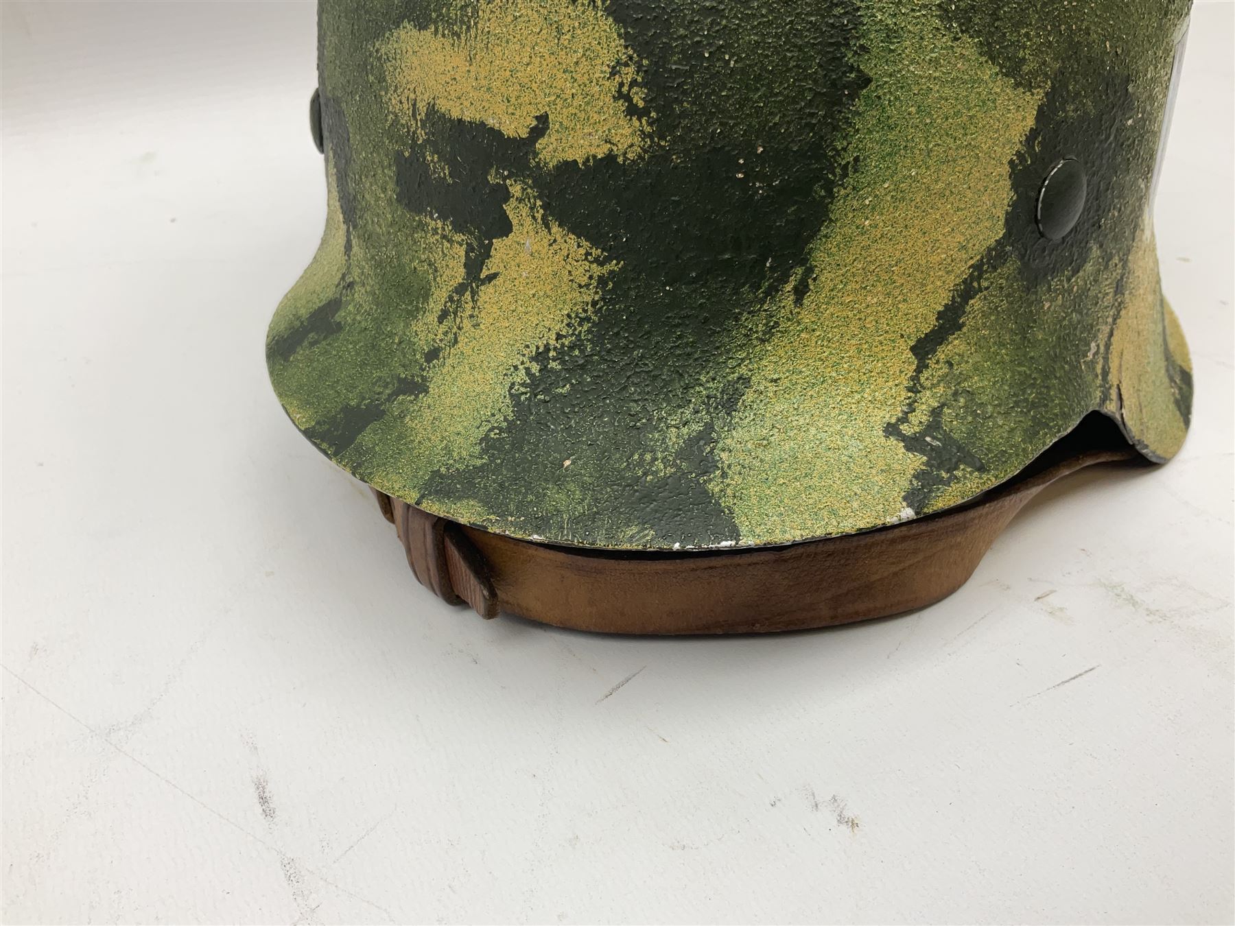 Fully restored German steel helmet, the camouflage painted exterior with two decals and replacement leather liner