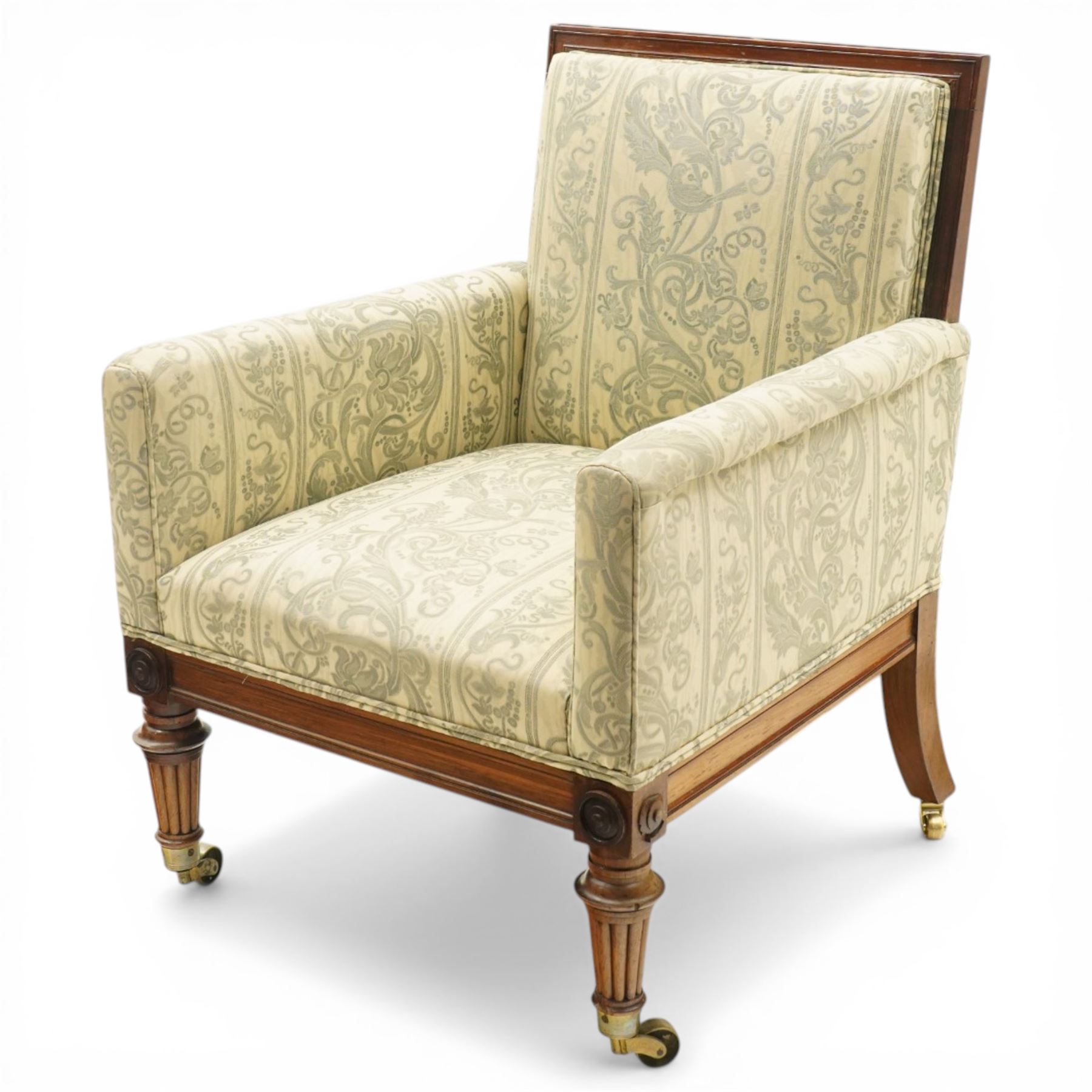 William IV rosewood framed library armchair, squared form with green on ivory ground upholstery, moulded lower seat rail with applied roundels over reeded supports, terminating to brass cups and castors