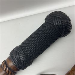 19th century wooden walking stick, the handle carved as a snake within a clenched fist, the cane carved with foliate and cross hatched decoration, with a metal spike to base, together with a turned wooden walking stick, with lacquered rope nautical knot handle, tallest L96.5cm