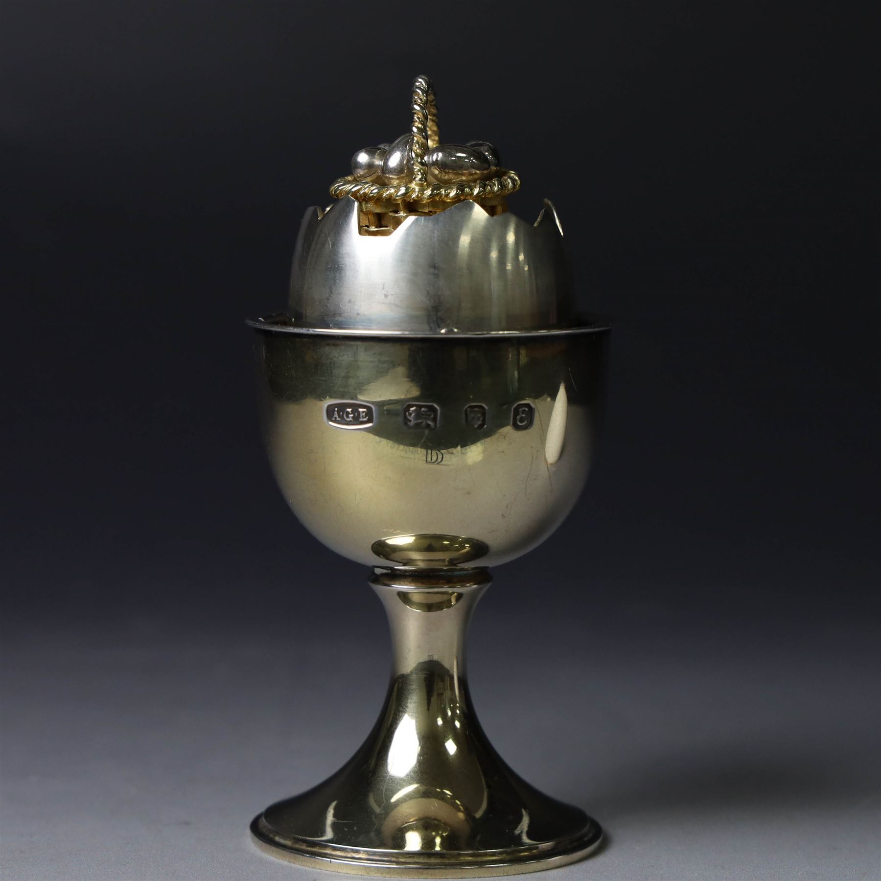 Late 20th century silver-gilt novelty surprise egg by Anthony Gordon Elson, the egg cup containing a  removeable shell, lifting to reveal a parcel gilt egg basket beneath, hallmarked Anthony Gordon Elson, London 1979, H11cm