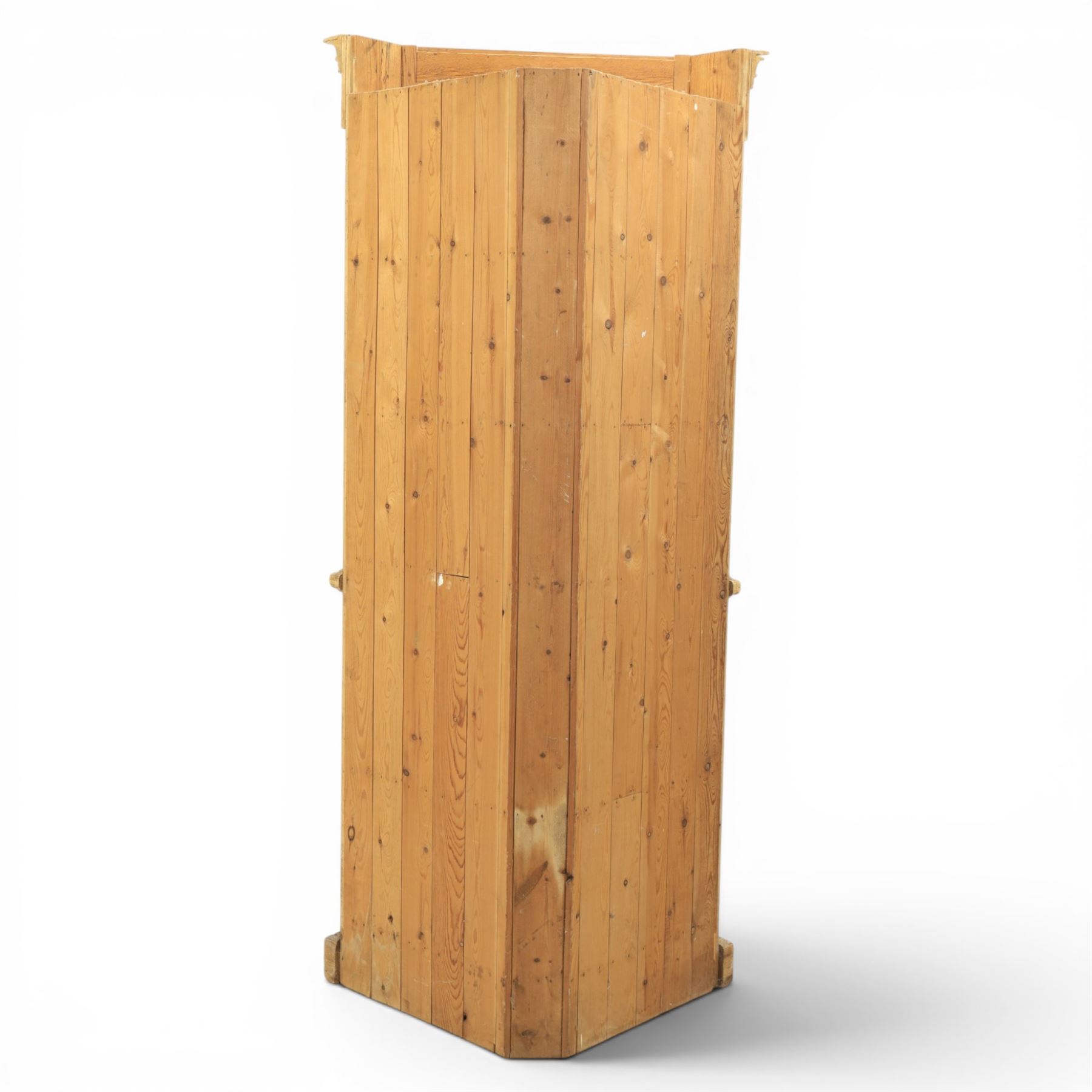 19th century stripped pine corner cabinet, projecting cornice flanked by fluted sides, astragal glazed upper door with brass knob, lower section with fielded panelled door, raised on a shaped plinth base 