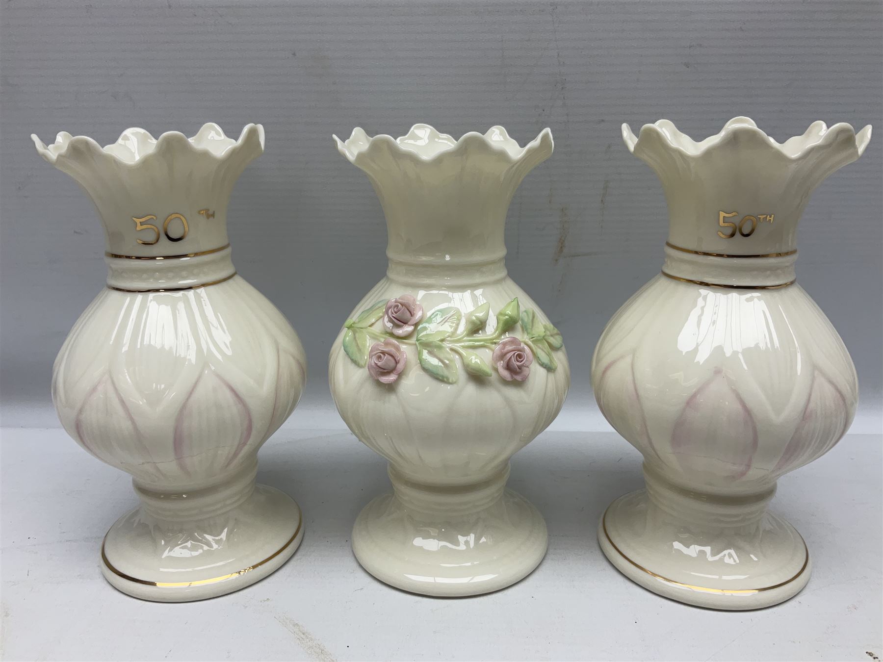 Five late 19th/early 20th century and later Belleek vases, comprising pair of Lotus Blossom examples, shamrock tree trunk vase, twin handled shamrock vase and a baluster form vase decorated with applied roses, all with printed marks beneath, tallest H16cm