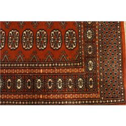Bokhara hand-knotted carpet, terracotta ground with repeating rows of Tekke guls interspersed with geometric motifs, enclosed by multiple stylised floral and geometric borders, with fringed ends