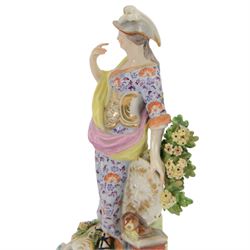 18th century Derby porcelain figure, circa 1775, modelled as Minerva, standing with mask shield, books and owl, against flowering bocage, upon a scroll base encrusted with flowers, H23cm