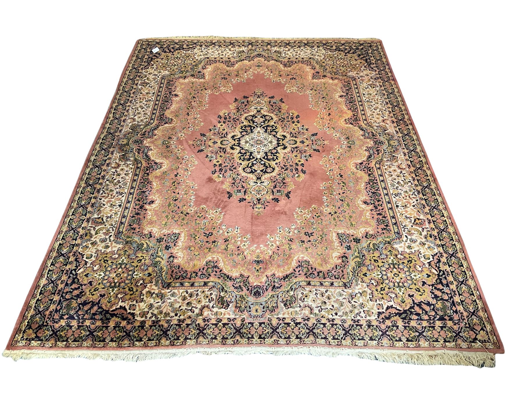 Large Persian design peach ground carpet, the field decorated with floral medallion, multi-band border decorated with repeating flower head pattern
