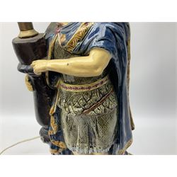 Composite table lamp modelled as a Roman Emperor donning blue robes, upon quatrefoil base modelled with rams heads and winged cherubs, H56cm excl fitting