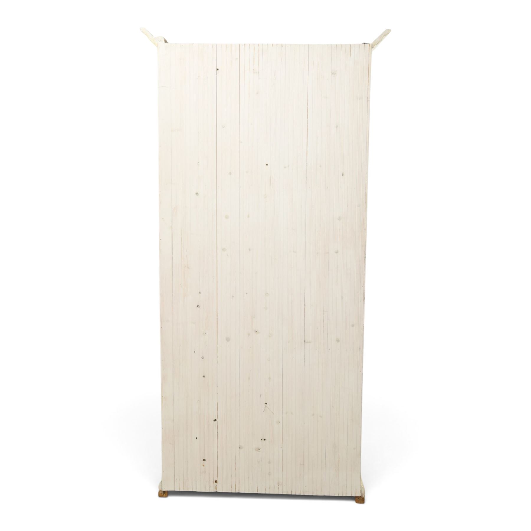 Traditional white painted pine display cabinet, projecting cornice above two glazed doors enclosing five fixed shelves, tongue and groove back raised on a plinth base