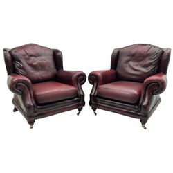 Thomas Lloyd - three-piece lounge suite, comprising of traditional shape two seat sofa (W190cm H80cm) and a pair of wingback armchairs (W100cm H91cm), each with rolled arms over turned supports with brass castors, upholstered in oxblood red leather