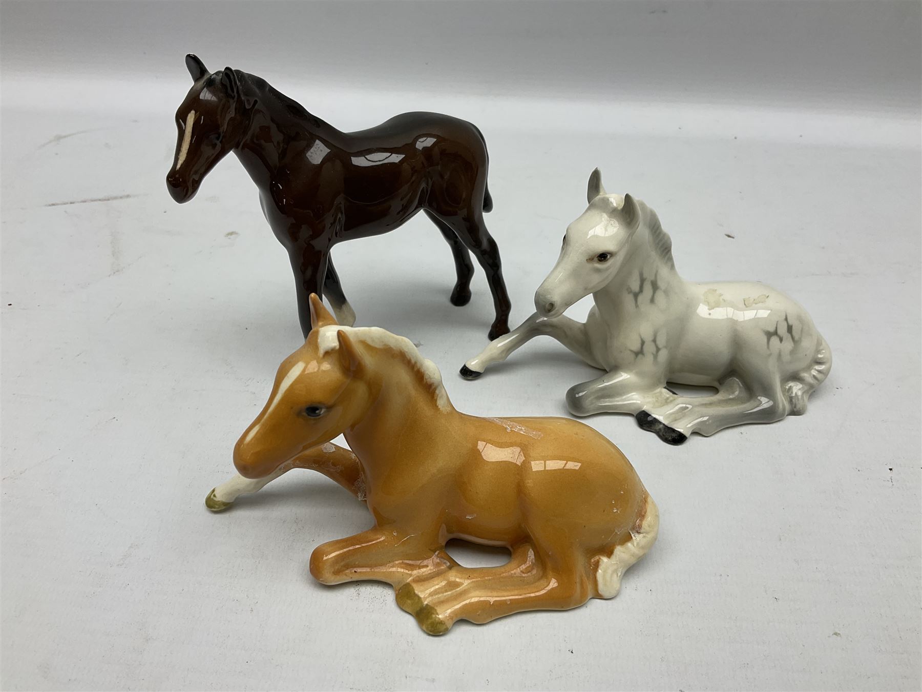 Three Beswick figures of horses, comprising Palomino foal 915, Dapple Grey foal and bay, together with Bing & Grondahl 1852 fledging sparrow modelled as a hungry baby bird and two other animal figures