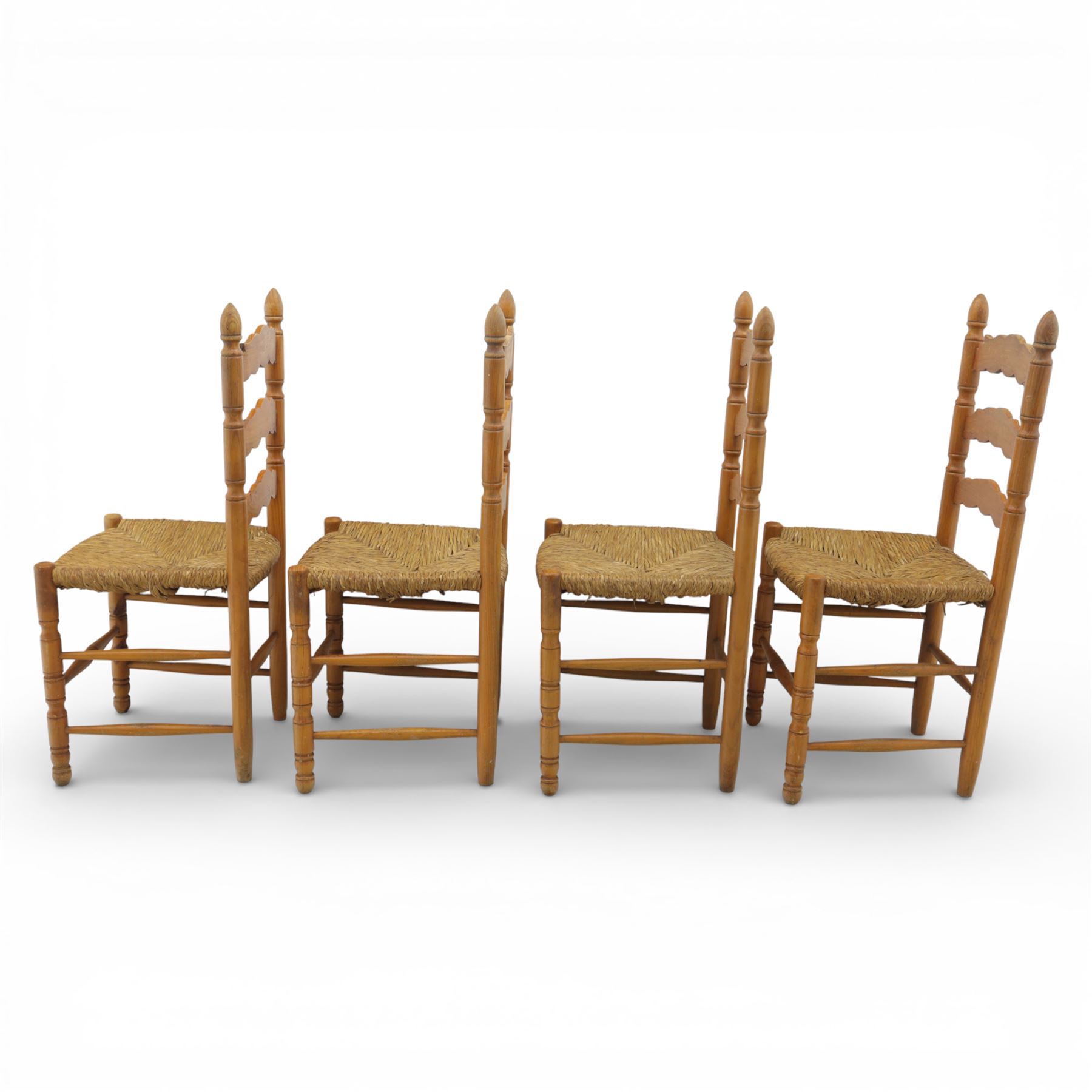 Late 20th century pine farmhouse dining table and four chairs, the rectangular plank top with rounded corners over two frieze drawers fitted with turned knob handles, raised on turned legs, the chairs with shaped ladder backs and turned finials, rush seats in a herringbone weave, on turned supports united by stretchers
