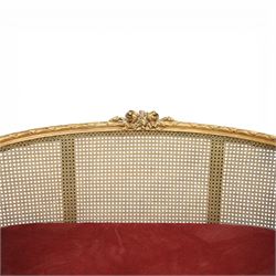 19th century giltwood and gesso settee, with shaped crest rail centred by carved floral detail, the cane back with vertical divisions, upholstered seat with loose cushion, raised on fluted tapering legs