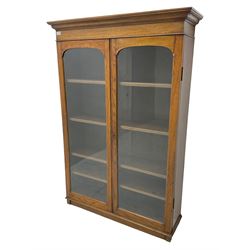 Victorian design oak display cabinet or bookcase, projecting cornice over two glazed doors, enclosing four adjustable shelves