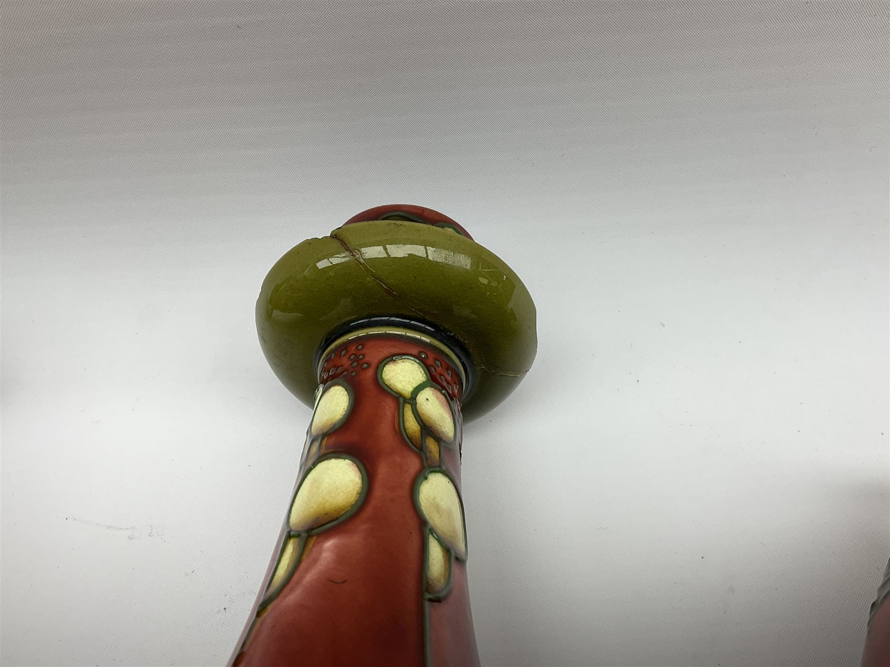 Minton Secessionist vase, with tube-lined stylised flower head decoration upon a red and green ground, printed mark to base 'Minton Ltd, No. 31', together with a matching pair of Minton Secessionist candle sticks, candlestick H17cm