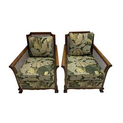 Early 20th century bergère lounge suite, mahogany framed with cane work back and sides, acanthus scroll carved uprights - three seat sofa (W167cm, H82cm, D83cm), and pair matching armchairs (W78cm), loose cushions upholstered in acanthus leaf scroll fabric with scatter cushions