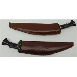  Pair of Kukri knives, 34cm single edge curved steel blades with brass mounted horn grips in leather covered wooden sheaths, one with two smaller knives, L48cm (2)  