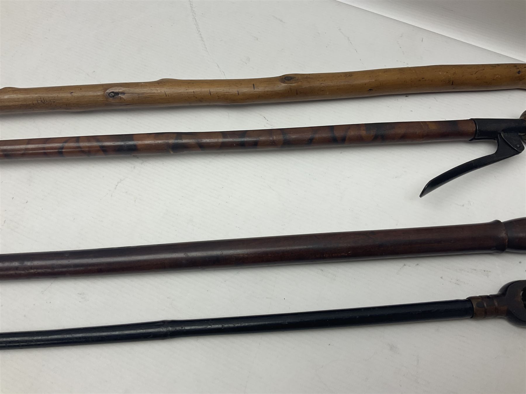 Two late 19th century fruit picker canes, the first example a French ebonised bamboo cane, with pair of fruit scissors to base, the handle stamped Cueille Fruit, the second example with grabbing action, the cap stamped A C Harris, Leicester, together with two other 19th century canes, one with fork and the other with hoe