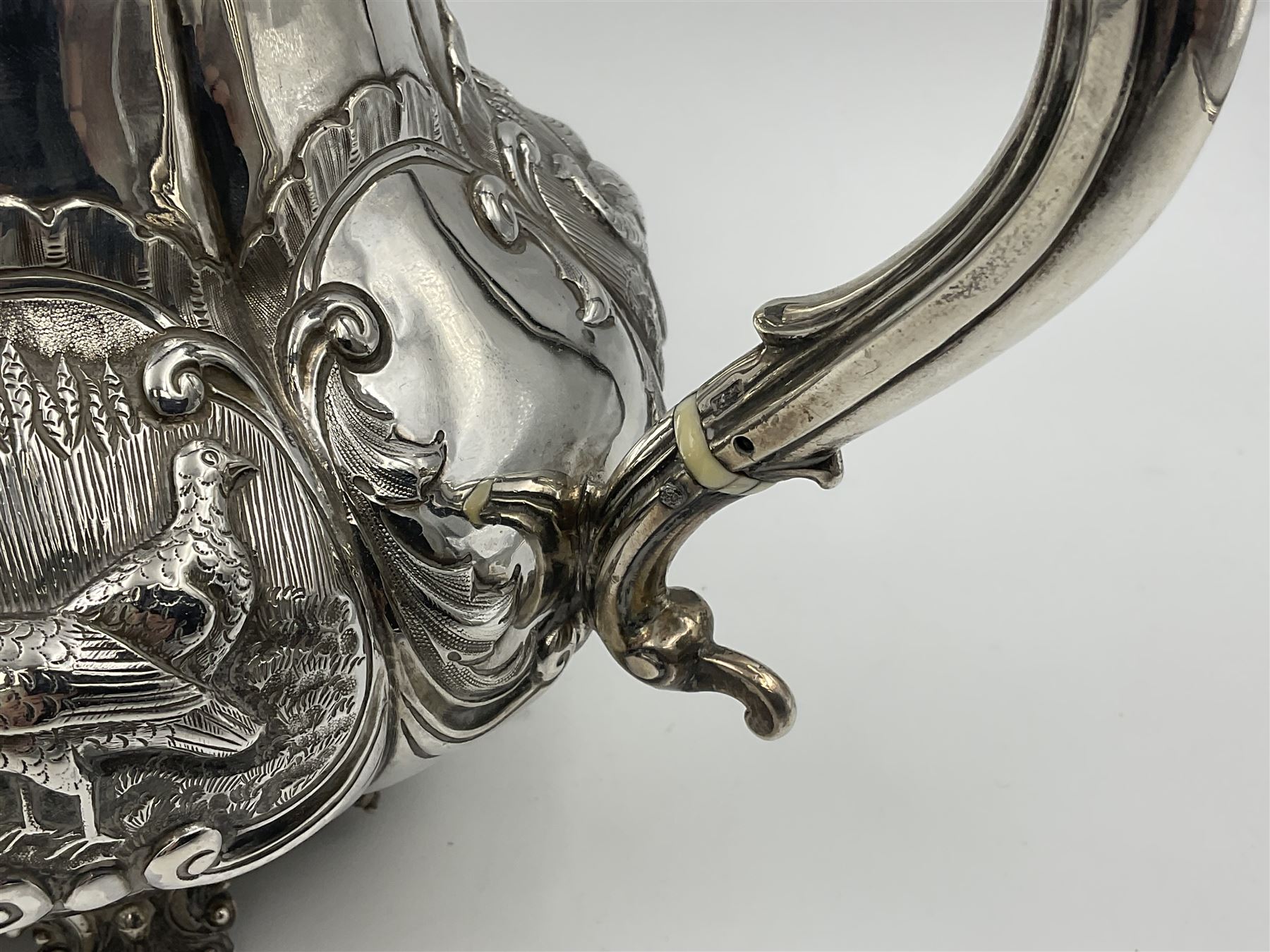 Victorian silver three piece tea service, comprising teapot, twin handled open sucrier, and milk jug, each of bellied form with acanthus capped scroll handles, the sides embossed with alternating scroll edged vacant panels and panels containing a pair of birds, upon four palmette feet, the teapot with ivory insulators to handle, and bird finial to the hinged domed cover, hallmarked William Hunter & Son, London 1861, teapot H19cm, including handles sucrier H13.5cm, including handle milk jug H12cm

This item has been registered for sale under Section 10 of the APHA Ivory Act