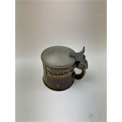 Arts and Crafts or Jugendstil tankard by Richard Riemerschmid, circa 1906, the cylindrical stoneware body reading 'Gaudeamus Igitur' (therefore let us rejoice), and finished in a brown glaze, with engraved slightly domed hinged lid, impressed mark beneath for Reinhold Merkelbach Grenzhausen, model number 2026 W, H14.5cm 