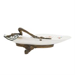 18th century porcelain dish, attributed to Chantilly, circa 1740-1750, with later ormolu mounted handle and feet, the dish of moulded shell form, painted in the Kakiemon pallet with an exotic bird and grasshopper amidst flowers and foliage, with foliate ormolu handle, and upon three scrolling foliate feet, possible obscure Chantilly mark beneath, including handle H10cm W31cm

A letter from the Ashmolean Museum accompanied the dish when it entered the current vendor's family collection. In the letter, Dr. Impey noted that the painting is European, possibly Dutch. The general consensus was that the shell dates to the 18th century, with the ormolu mounts likely added in the 19th century. However, the factory of origin remained unidentified. The letter was signed by Ian Lowe in 1974. Further consultation at the time with four members of staff at the Victoria and Albert Museum yielded differing opinions, with suggestions including Chantilly and Bow. The piece has been attributed to Chantilly partly due to what appears to be a partially obliterated horn motif beneath.