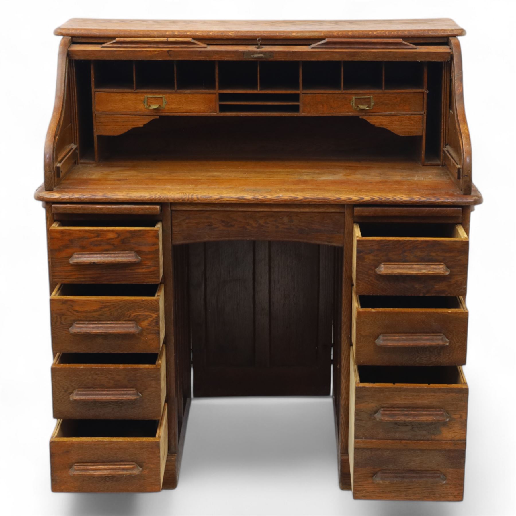 Early 20th-century oak roll-top desk with tambour shutter, enclosing a fitted interior of pigeon holes and small drawers, and pedestal base fitted with nine drawers with moulded handles, raised on plinth base 